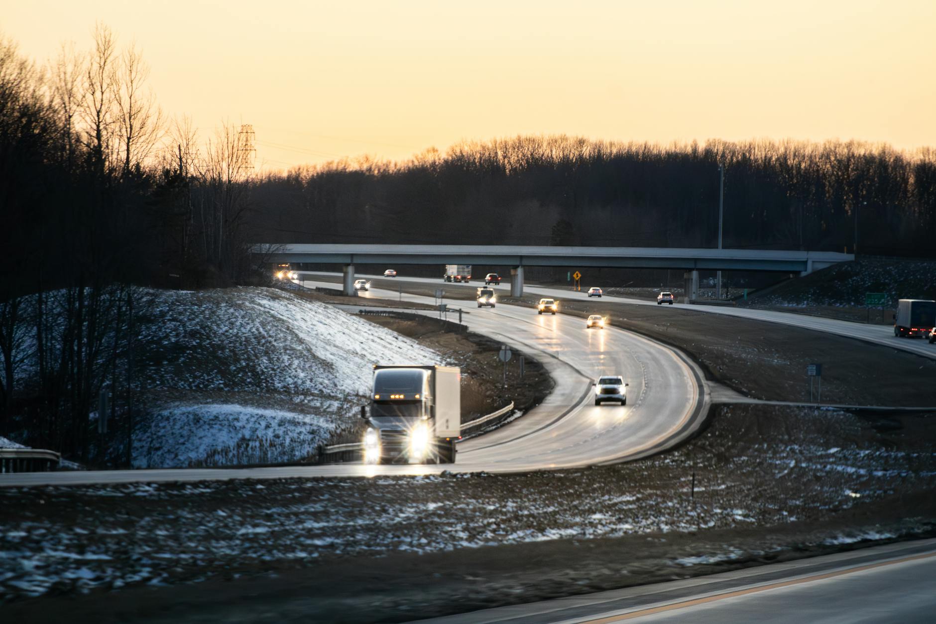 Samochody i ciężarówki jadą zimową autostradą o zmierzchu