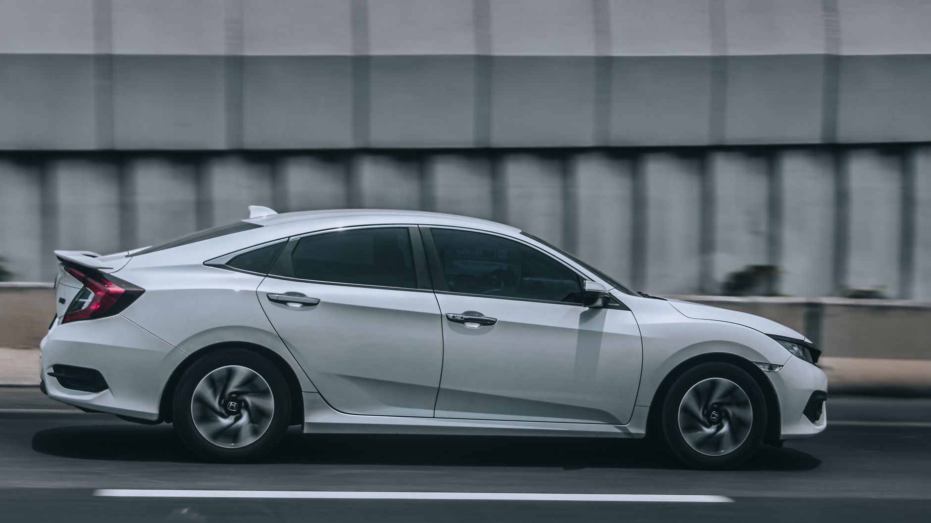 Białe auto jedzie szybko miejską ulicą, symbolizując dynamiczną jazdę