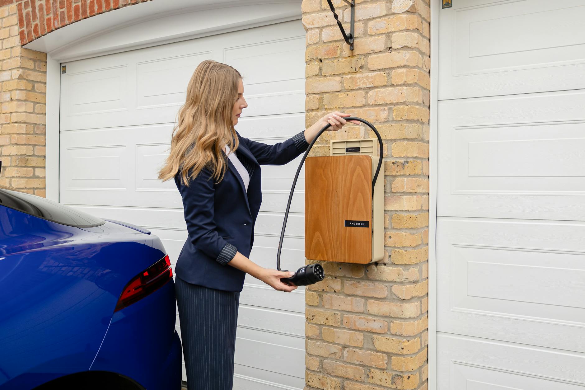 Kobieta podłącza auto elektryczne do domowej ładowarki w garażu