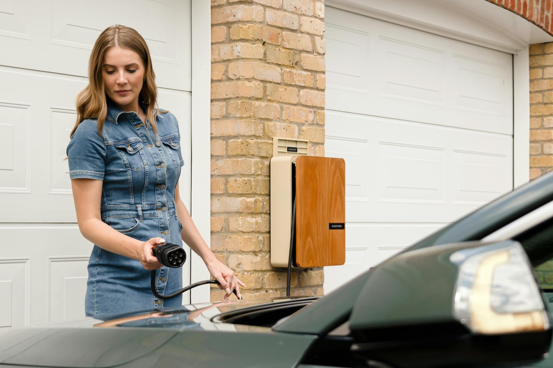 Kobieta podłącza auto elektryczne do domowej stacji ładowania