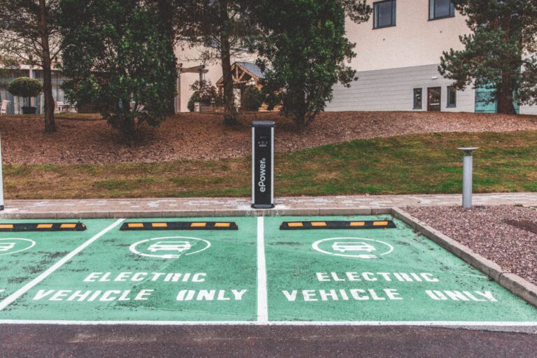 Zielony samochód elektryczny przy stacji ładowania w mieście