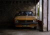 Żółty klasyczny Opel zaparkowany przy kamiennym garażu